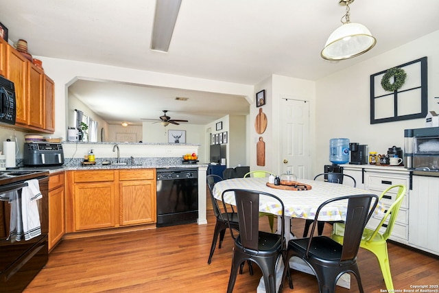 kitchen featuring ceiling fan, light wood-type flooring, brown cabinets, a peninsula, and black appliances