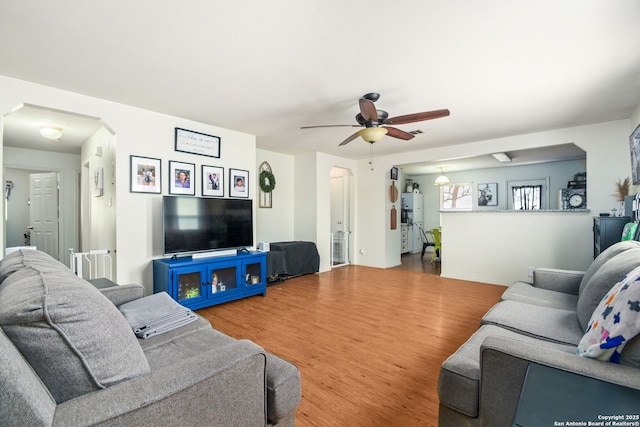 living area with ceiling fan, arched walkways, and wood finished floors