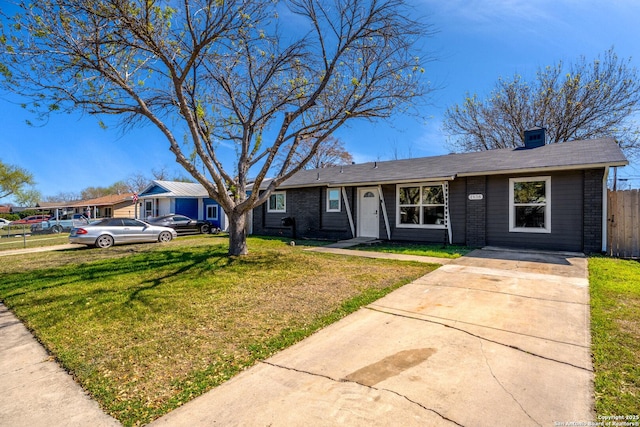 ranch-style house featuring brick siding, a front lawn, and fence