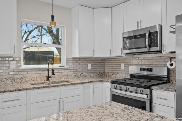 kitchen featuring backsplash, white cabinets, appliances with stainless steel finishes, and a sink