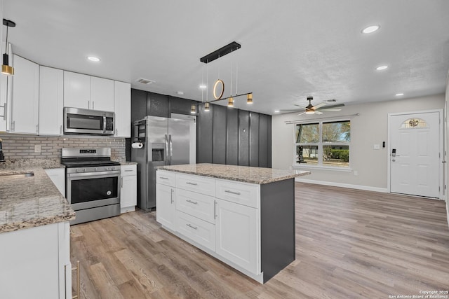 kitchen with visible vents, backsplash, a center island, light wood-style flooring, and appliances with stainless steel finishes