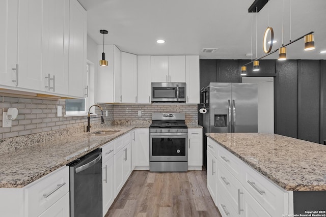 kitchen featuring visible vents, a sink, light stone counters, appliances with stainless steel finishes, and light wood finished floors