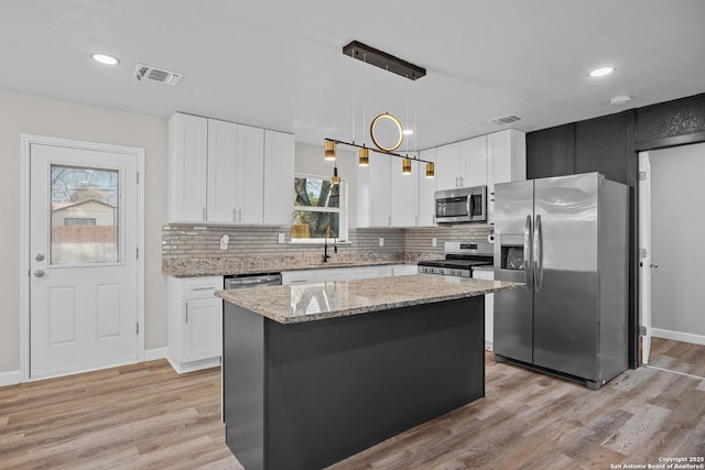 kitchen featuring visible vents, a kitchen island, appliances with stainless steel finishes, and light wood finished floors