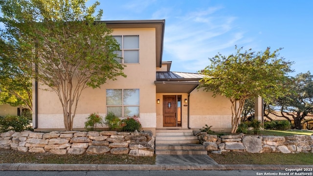 view of front of property with stucco siding, metal roof, and a standing seam roof