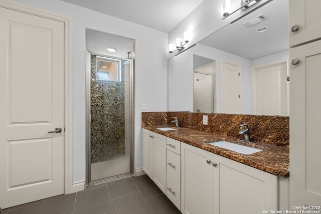 bathroom with tile patterned flooring, visible vents, a shower stall, double vanity, and a sink