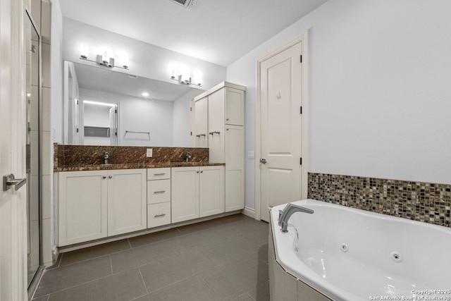 bathroom with tile patterned flooring, a tub with jets, a sink, and double vanity