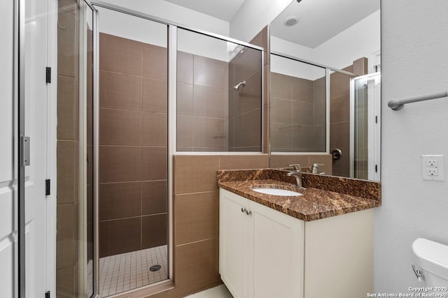 bathroom with toilet, a stall shower, and vanity