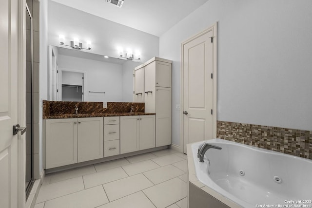 bathroom featuring a sink, a jetted tub, a shower stall, tile patterned flooring, and double vanity