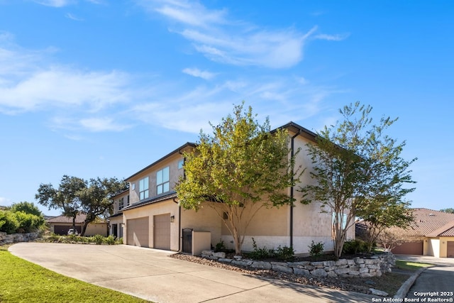 view of property exterior with stucco siding, a garage, and driveway