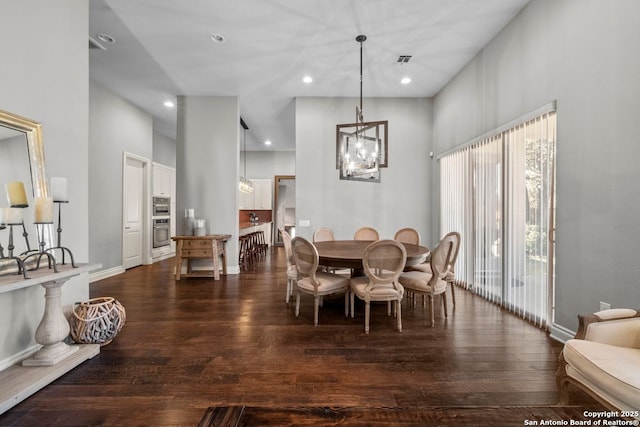 dining area featuring baseboards, dark wood finished floors, a high ceiling, recessed lighting, and a chandelier