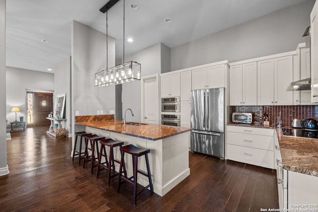 kitchen with tasteful backsplash, dark wood-style floors, dark stone countertops, and freestanding refrigerator