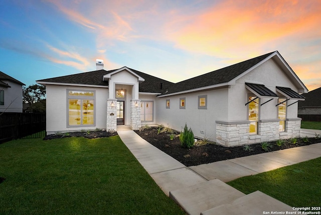 view of front of house with a shingled roof, a chimney, a front lawn, stucco siding, and stone siding