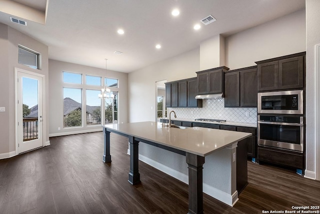 kitchen featuring tasteful backsplash, an island with sink, visible vents, and appliances with stainless steel finishes