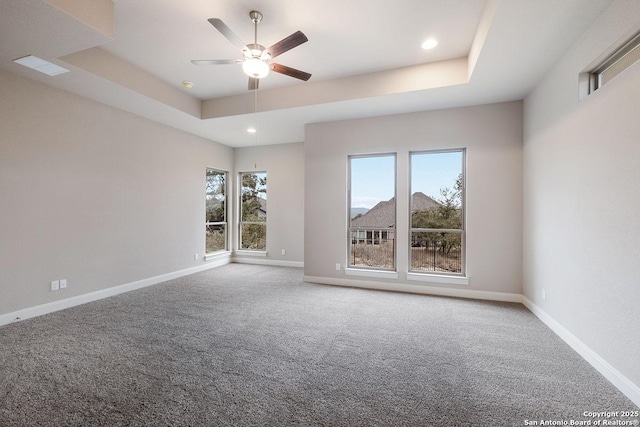 carpeted empty room featuring recessed lighting, ceiling fan, a raised ceiling, and baseboards