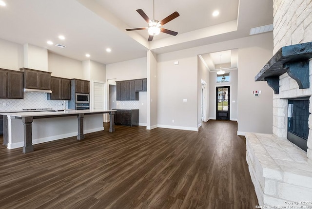 kitchen with a breakfast bar area, visible vents, a high ceiling, dark brown cabinetry, and stainless steel microwave