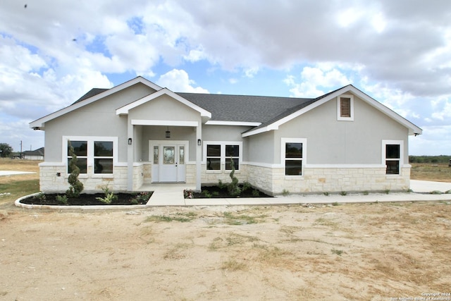 view of front of home with stucco siding, stone siding, and a shingled roof