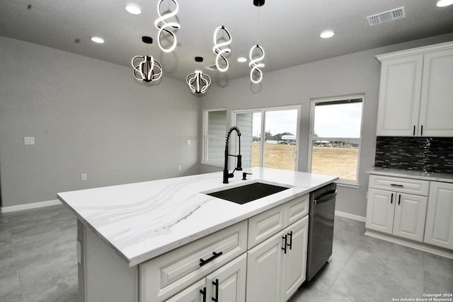 kitchen featuring dishwashing machine, visible vents, an island with sink, a sink, and decorative backsplash