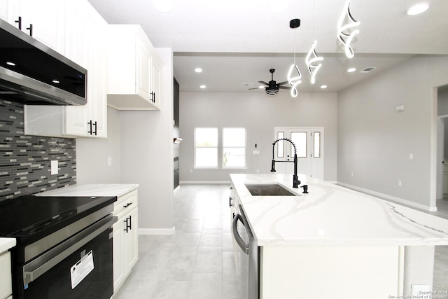 kitchen with light stone counters, decorative backsplash, white cabinets, stainless steel appliances, and a sink