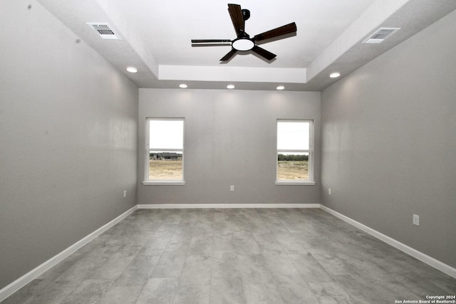 empty room with visible vents, recessed lighting, baseboards, and a tray ceiling