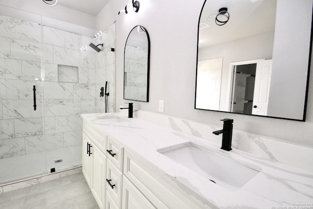 bathroom with a sink, marble finish floor, a stall shower, and double vanity