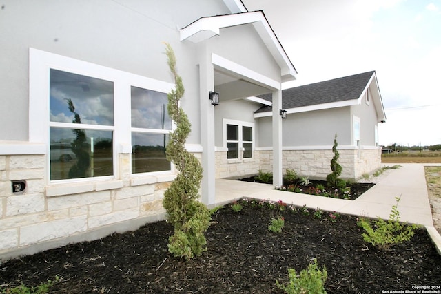 view of side of property featuring stone siding and stucco siding