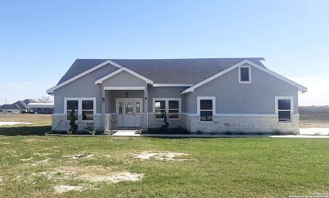 view of front of home with stucco siding, stone siding, roof with shingles, and a front yard