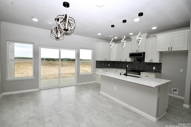 kitchen with decorative backsplash, stainless steel microwave, and white cabinetry