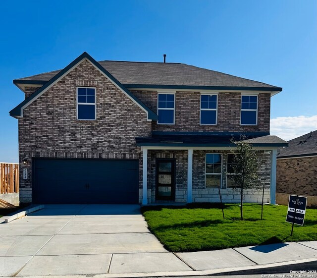 traditional home with a front yard, a garage, brick siding, and driveway