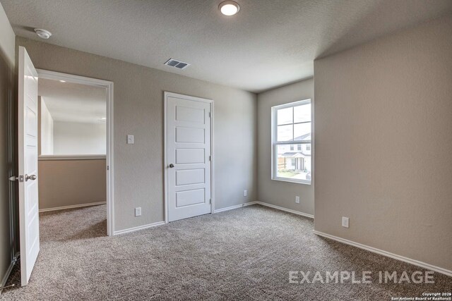 7015 Comanche Cave, San Antonio, TX 78247 - unfurnished bedroom featuring visible vents, carpet floors, a textured ceiling, and baseboards