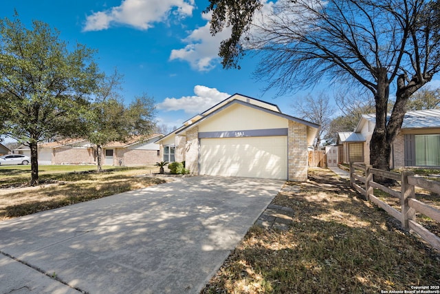 view of front of house with brick siding, an attached garage, concrete driveway, and fence