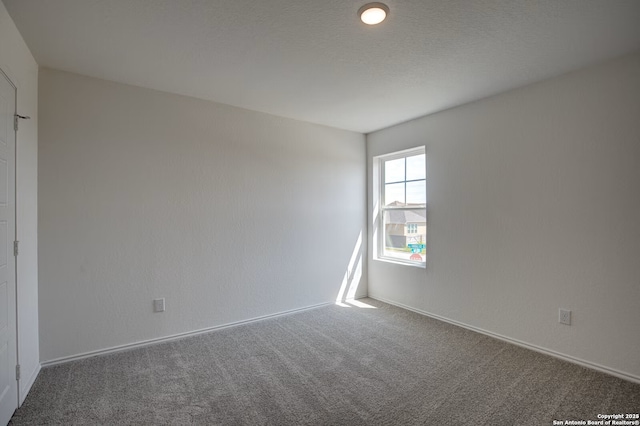 carpeted empty room featuring baseboards and a textured ceiling