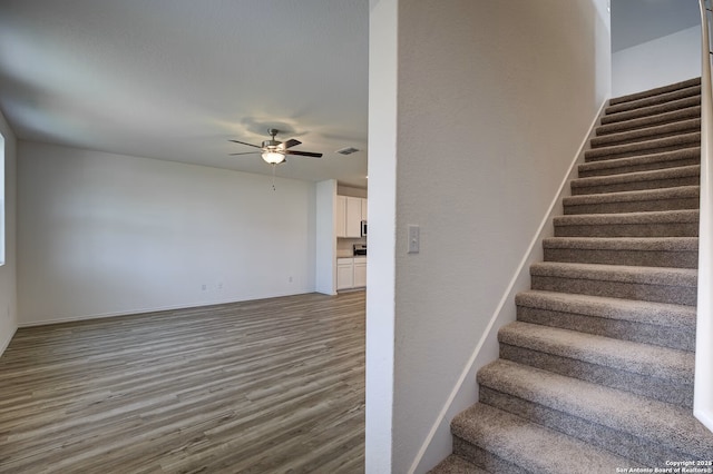 stairs with visible vents, baseboards, ceiling fan, and wood finished floors