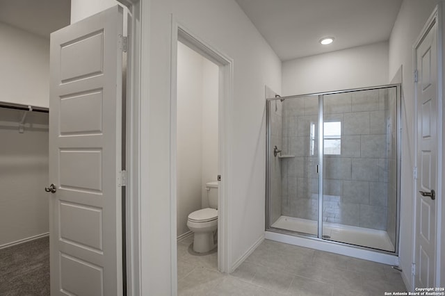 bathroom with tile patterned flooring, a stall shower, toilet, and baseboards