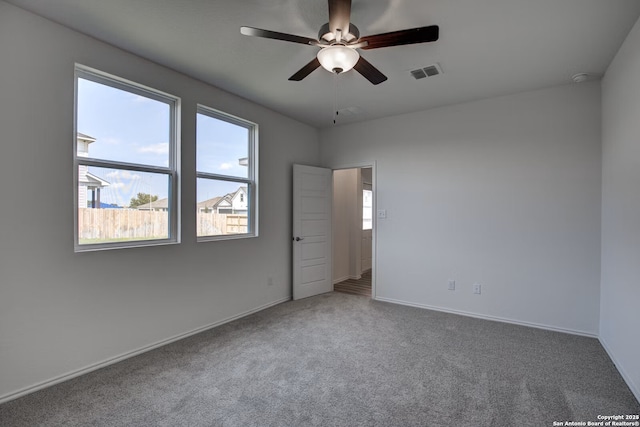 unfurnished room with visible vents, carpet flooring, baseboards, and a ceiling fan