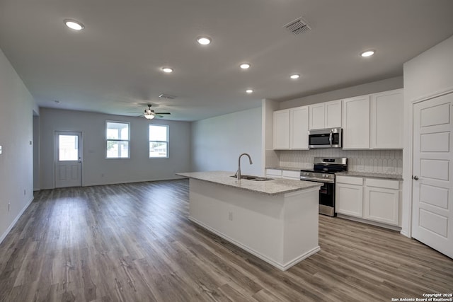 kitchen featuring tasteful backsplash, visible vents, a center island with sink, stainless steel appliances, and a sink