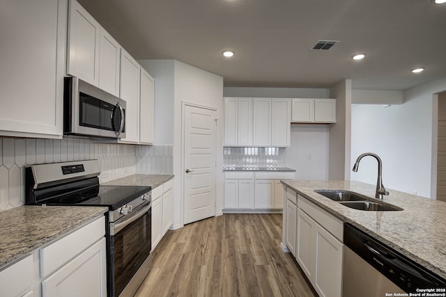 kitchen featuring visible vents, a sink, white cabinets, appliances with stainless steel finishes, and light wood-type flooring