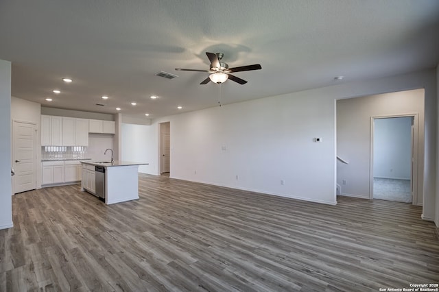 unfurnished living room with a sink, visible vents, wood finished floors, and a ceiling fan