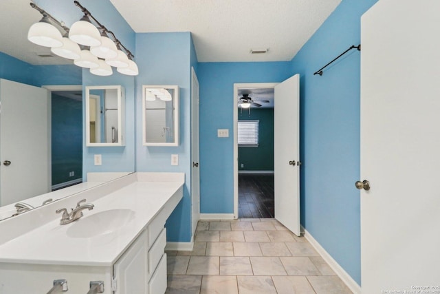 bathroom with visible vents, a textured ceiling, baseboards, ceiling fan, and vanity