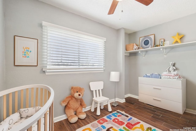 bedroom featuring a crib, dark wood-type flooring, and baseboards