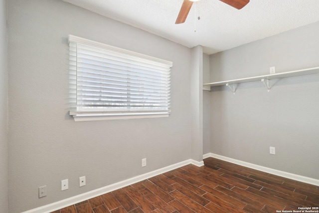 unfurnished room featuring baseboards, dark wood-style floors, and a ceiling fan