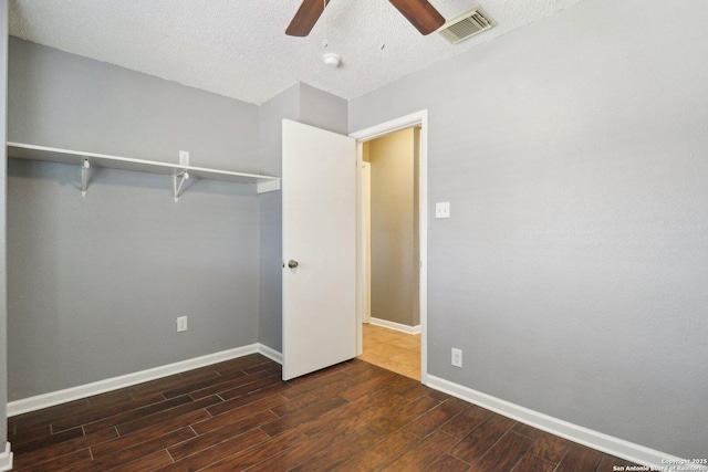 unfurnished bedroom featuring visible vents, baseboards, dark wood-style floors, a textured ceiling, and a ceiling fan