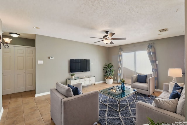 living room featuring baseboards, visible vents, a textured ceiling, and a ceiling fan