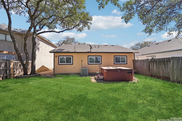 back of property with central air condition unit, a yard, a fenced backyard, and a hot tub