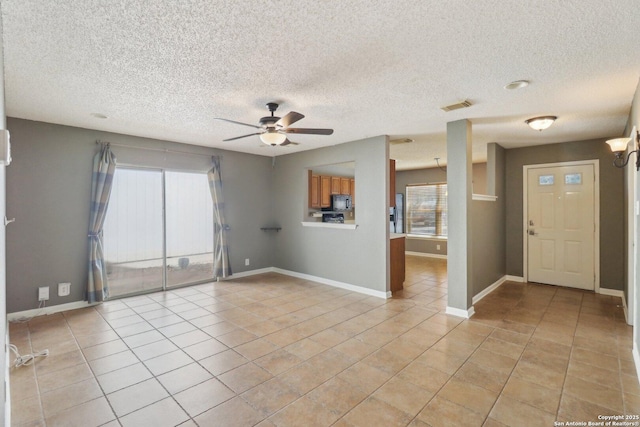 interior space featuring light tile patterned floors, visible vents, baseboards, and a ceiling fan