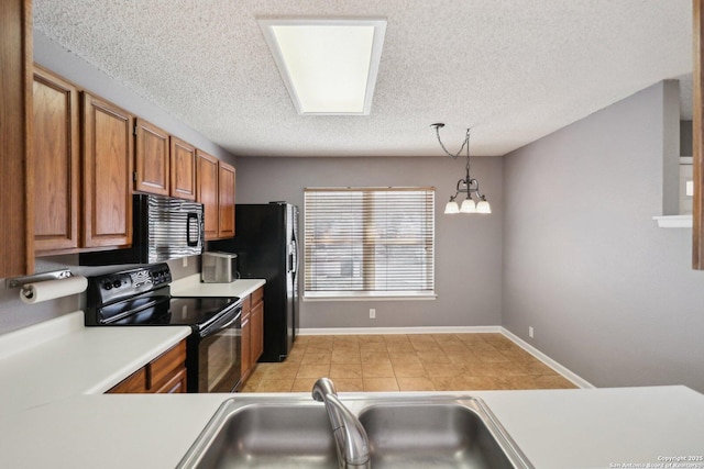 kitchen with decorative light fixtures, light countertops, brown cabinets, black appliances, and a sink