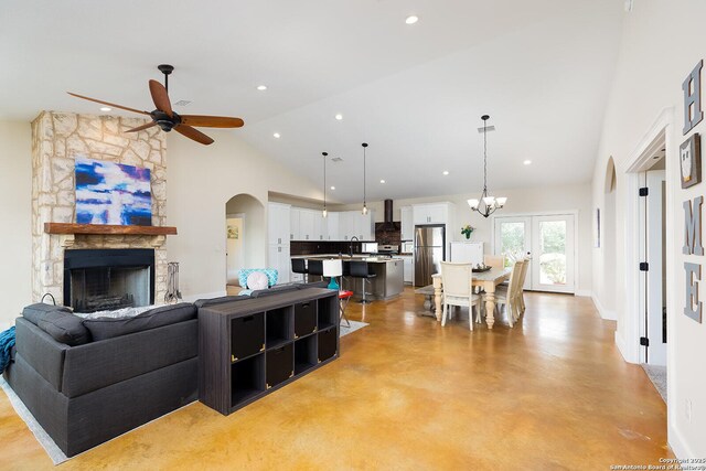 903 Panorama Pass, Horseshoe Bay, TX 78657 - living area featuring a fireplace, finished concrete flooring, high vaulted ceiling, arched walkways, and ceiling fan with notable chandelier