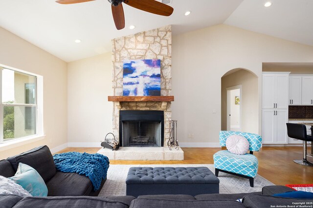 903 Panorama Pass, Horseshoe Bay, TX 78657 - living room with baseboards, arched walkways, a stone fireplace, a ceiling fan, and high vaulted ceiling