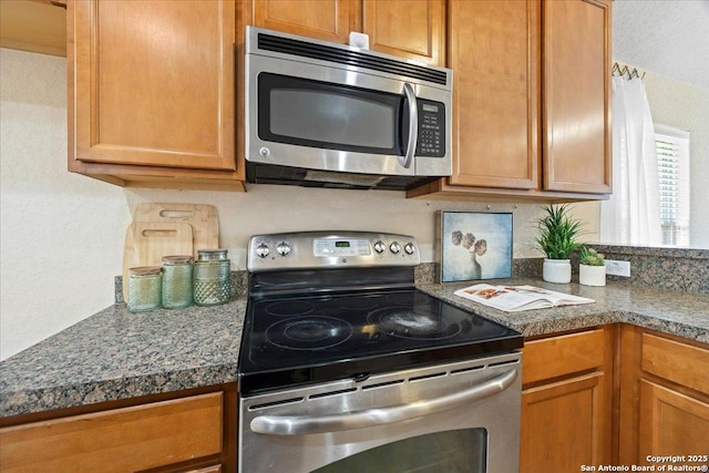 kitchen featuring dark countertops, appliances with stainless steel finishes, and brown cabinetry