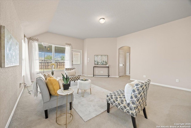 carpeted living room featuring arched walkways, a textured ceiling, baseboards, and vaulted ceiling