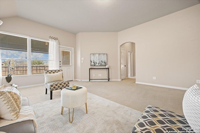 carpeted living room featuring arched walkways, lofted ceiling, and baseboards